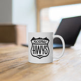 White mug with Scenic Hwys logo sitting on a table