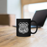 Black mug with Scenic Hwys logo sitting on a table